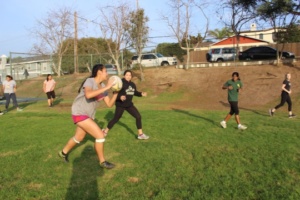 Girls Rugby player pass the bass to each other while running from one side of the field to another.