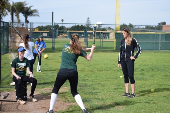 Varsity softball player Grace Herron swings and hits the ball into the net a few feet away from her at practice on Friday. Herron’s teammate threw the ball to her so she can help improve her swing.