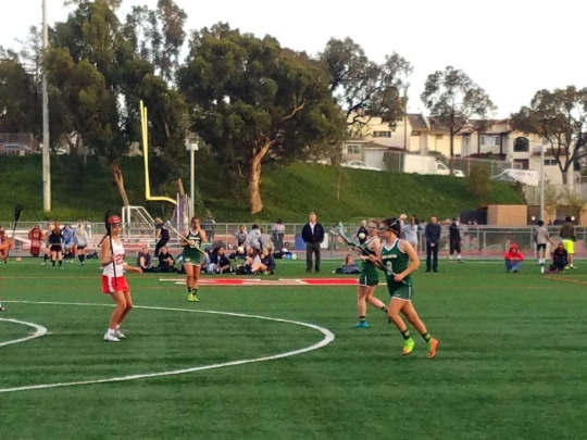 Costa senior Kelli Marks holds the ball in his stick as she runs towards the baseline. Kelli is looking for an opening to pass the ball, while guarding against a Redondo.